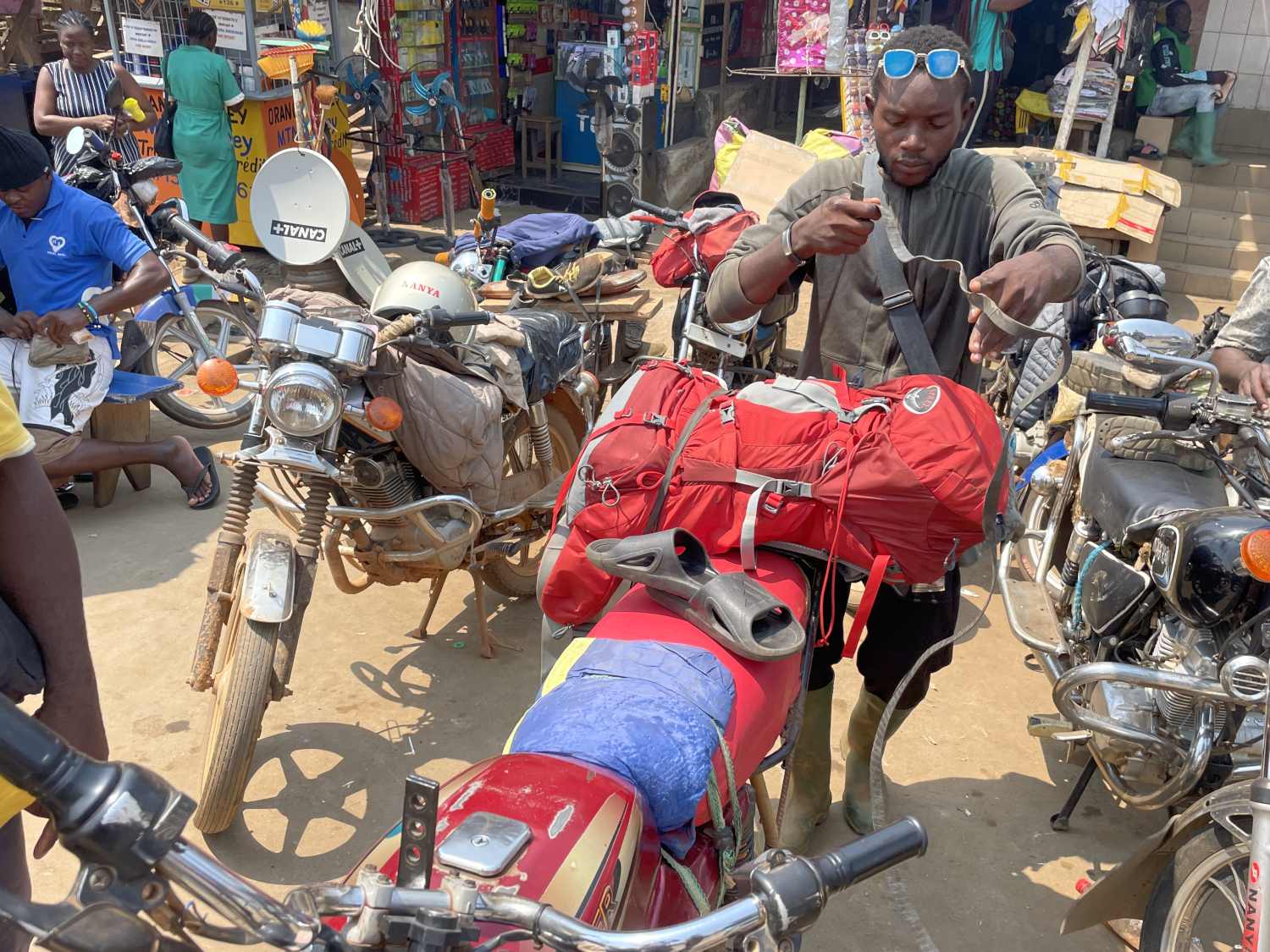 À la gare routière de Kribi, Patrick, moto-taxi, accroche le sac de Raphaël à l’aide vieilles chambres à air