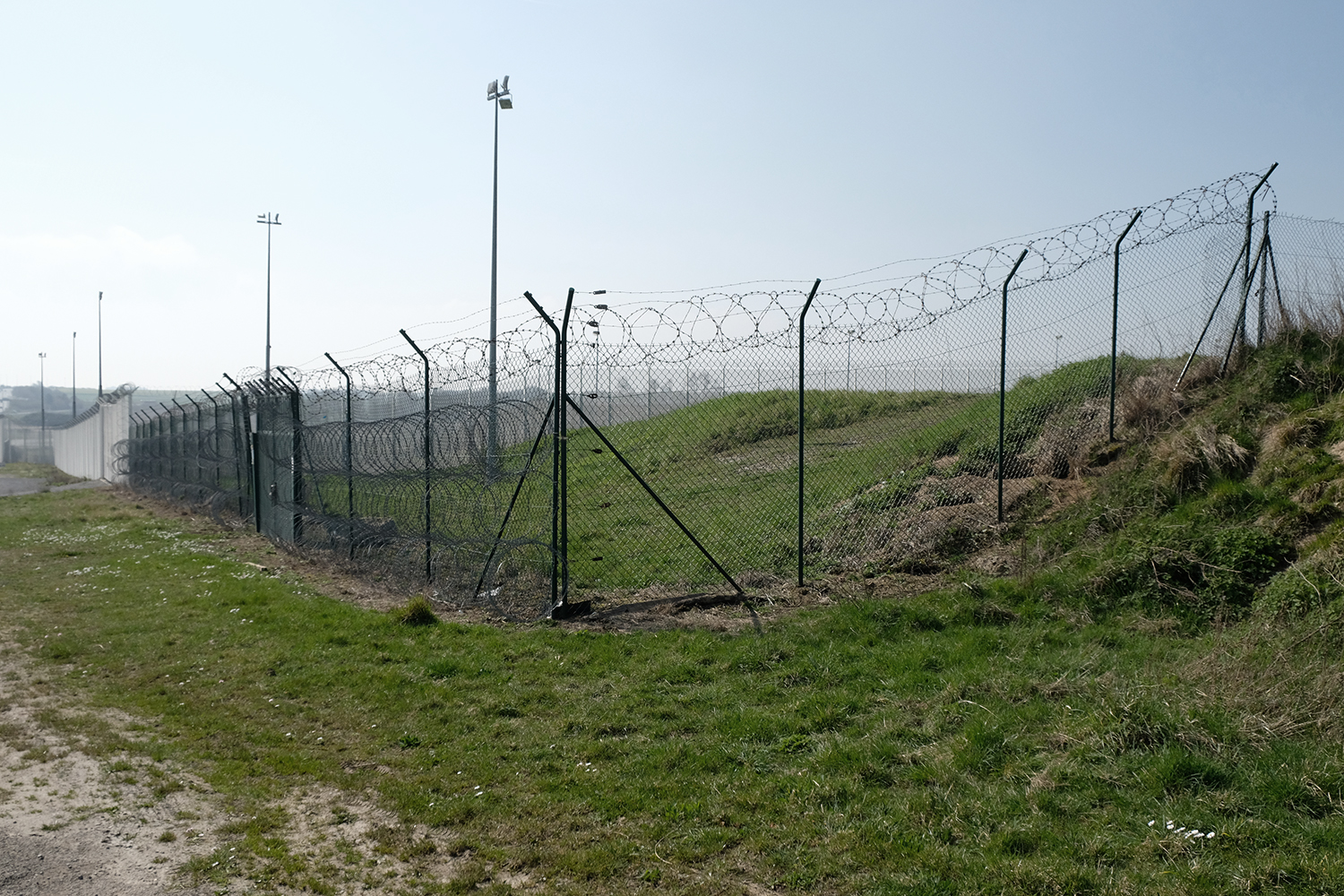 A quoi ressemble une frontière ? Des grilles et des barbelés, encore. Nous sommes cette fois-ci ente Coquelle et Sangatte. Derrière les grillages, en contre-bas, l’entrée du tunnel sous la manche. 